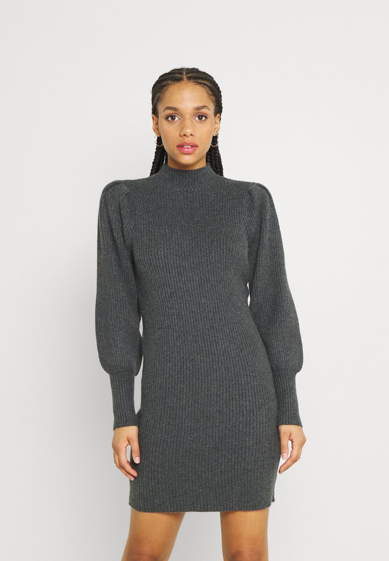 Vestido de punto acanalado gris oscuro con cuello alto, mangas largas abullonadas y un corte ceñido, que presenta aberturas laterales y una textura suave.