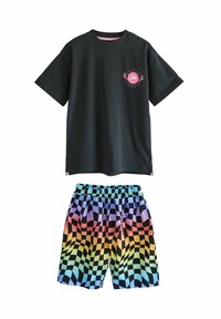 Svart bomullströja med en rosa grafik på bröstet, i kombination med flerfärgade rutiga shorts med ett gradientmönster i blått, rosa och gult.