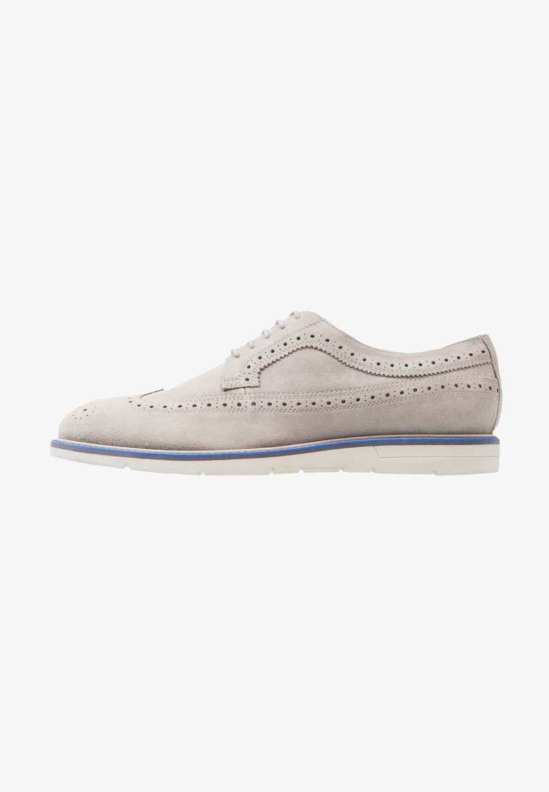 Chaussure brogue pour homme en daim gris clair avec perforations en forme d'aile, semelle blanche, bordure bleue et fermeture à lacets, vue de côté sur fond blanc.