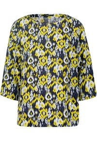 Locker sitzende Bluse aus einem Stoff mit einem kräftigen, gelben, marineblauen und weißen abstrakten Muster. Kurze Ärmel und ein weiter Ausschnitt.