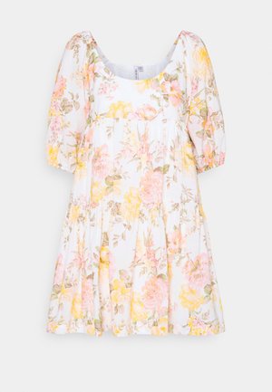 Biała sukienka w kwiaty z bufkami na krótkich rękawach, z okrągłym dekoltem i falbaniastą spódnicą z różowymi i żółtymi wzorami kwiatowymi.