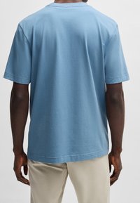 Světlomodré tričko s krátkým rukávem vyrobené z bavlny. Kulatý výstřih a volný střih s jemnými švy na rukávech a lemu.