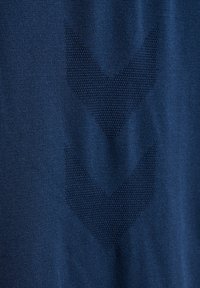 Marinblå tyg med ett strukturerat zigzag-mönster i en mörkare nyans av blått, som visar en slät yta och en sammanhållen design.