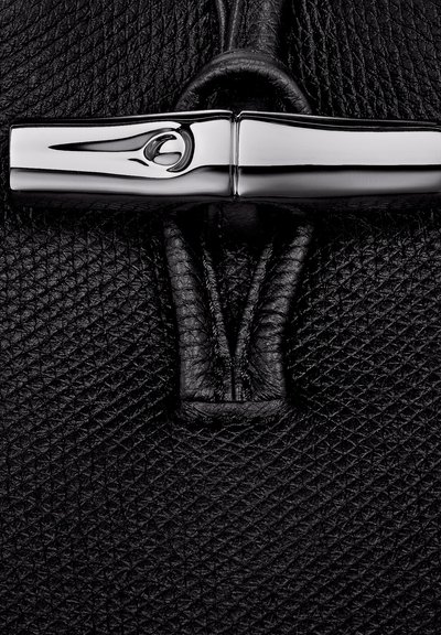 Schwarze Leder-Handtasche mit einer strukturierten Oberfläche, einem eleganten metallischen Verschluss und detaillierten Nähten im Bereich der Verschlusstechnik.