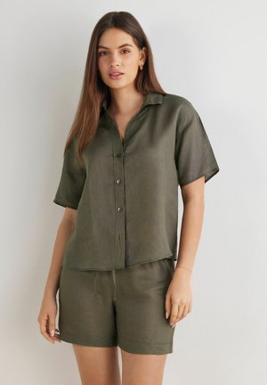 Olivengrøn skjorte i et blanding af linned med korte ærmer, knappet foran og med en let cropped kant, parret med matchende pull-on shorts.