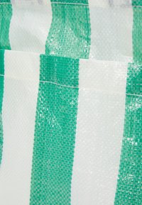 Gros plan d'un tissu tissé en plastique rayé vert et blanc avec des coutures visibles et une surface texturée.