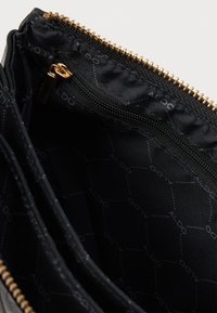 Must musträga kotike kuldse tõmblukuga ja sisemuses korduv "ALDO" muster. Sile tekstuur, kompaktne ja ristkülikukujuline kuju.