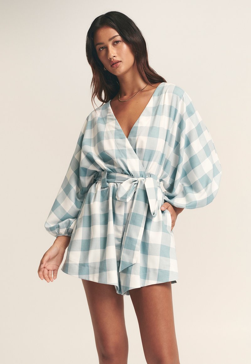 Apvyniojama suknelė šviesiai mėlynos ir baltos languotos spalvos, su ilgomis pūstomis rankovėmis, gilia iškirpte v formos ir diržu juosmenyje. Minkšta medžiaga.