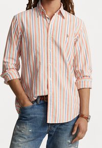 Camisa de botones con rayas verticales en coral, azul y blanco. Hecha de un tejido ligero con cuello clásico y mangas enrolladas.