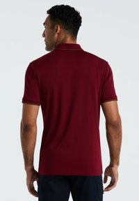 Bordeaux polo shirt met korte mouwen, uitgerust met een klassieke kraag en contrasterende afwerking aan de mouwen. Gladde textuur en tailormade pasvorm.