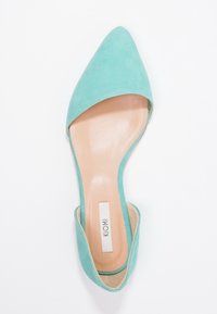 Turkos mocka spetsig flat sko med öppen häl och sidoutskärningar. Mjuk beige innersula med vit märkesetikett.