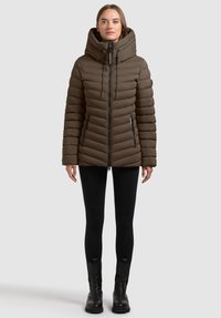 Hnědá péřová bunda s vysok�ým límcem a kapucí, s prošitými svislými panely, zipovými bočními kapsami a elastickými šňůrkami na stažení.