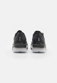 Baskets de sport noires avec une tige texturée, semelles intermédiaires blanches et semelles extérieures en caoutchouc. Présentent un logo réfléchissant et des détails d'accent sur le talon.