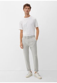 Lichtgrijze tapered broeken met een verstelbare tailleband en opgerolde manchetten, gecombineerd met een witte T-shirt met ronde hals en witte sneakers.