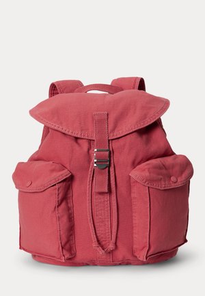 Zaino in tessuto rosso con patta, fibbia in metallo, due tasche frontali con bottone e spallacci su sfondo bianco.