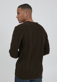 Pulover tricotat de culoare maro închis, cu modele de tip cable knit, forme de diamant și tiv striat. Design cu guler tip crew și detalii texturate pe spate.