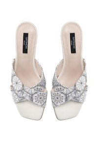 Scarpe con tacco alto a slingback con un motivo geometrico bianco e nero, dotate di pelle liscia, punta quadrata e una larga cinghia alla caviglia.