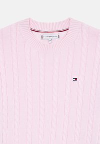 Helles rosa Strickpullover mit Rippkragen und kleinem Tommy Hilfiger-Logo auf der Brust gestickt.