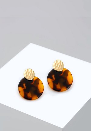 Boucles d'oreilles rondes en acrylique écaille avec clous circulaires dorés martelés sur une plateforme carrée blanche.