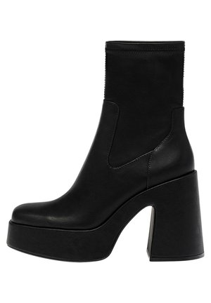 Czarny skórzany botek za kostkę z wysokim blokowym obcasem, platformą oraz elastycznymi panelami bocznymi. Gładka tekstura z minimalnymi detalami w szwach.
