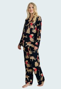 Black pajama set featuring a leopard and holiday-themed print with red and green accents, made of soft fabric with a relaxed fit.