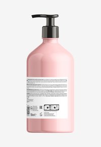 Rosa plastflaske med en svart pumpehette, med en teksturert overflate. Baketiketten inneholderProduktinformasjon og ikoner for resirkulering.