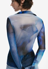 Long-sleeve sheer top featuring a blue and gray abstract pattern. Smooth texture with a fitted design, collar, and seamless transitions at cuffs.