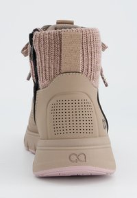 Baskets beiges avec un col en tricot rose, un panneau arrière texturé et des détails perforés sur le talon, avec un accent noir.