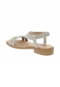 Sandal de color beige claro con un tacón de madera plano, que presenta rhinestones decorativos en las correas y una correa trasera texturizada para un detalle adicional.