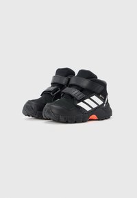 Mustad spordijalatsid tekstureeritud pealmise osaga, kahe takjakinnitusega, kolmete valgete triipudega külgedel ning punase aktsendiga tallal.