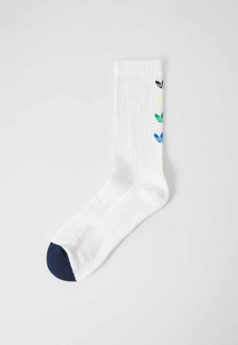 Bela bombažna nogavica z vertikalnim rebrastim vzorcem, mornarsko modrim prstom in pisanimi listnatimi motivi v zeleni, modri, rumeni in temno modri barvi ob strani.