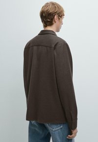 Bruine wolmix shirt met een comfortabele pasvorm, voorzien van een kraag, knoopmanchetten en een soepele textuur. De achteraanzicht toont schoudernaden en de zoom.