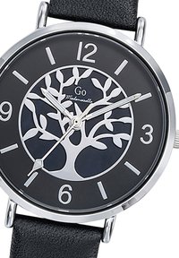 Montre analogique avec un boîtier en acier inoxydable, un cadran noir arborant un design d'arbre, des index horaires blancs et un bracelet en cuir noir.