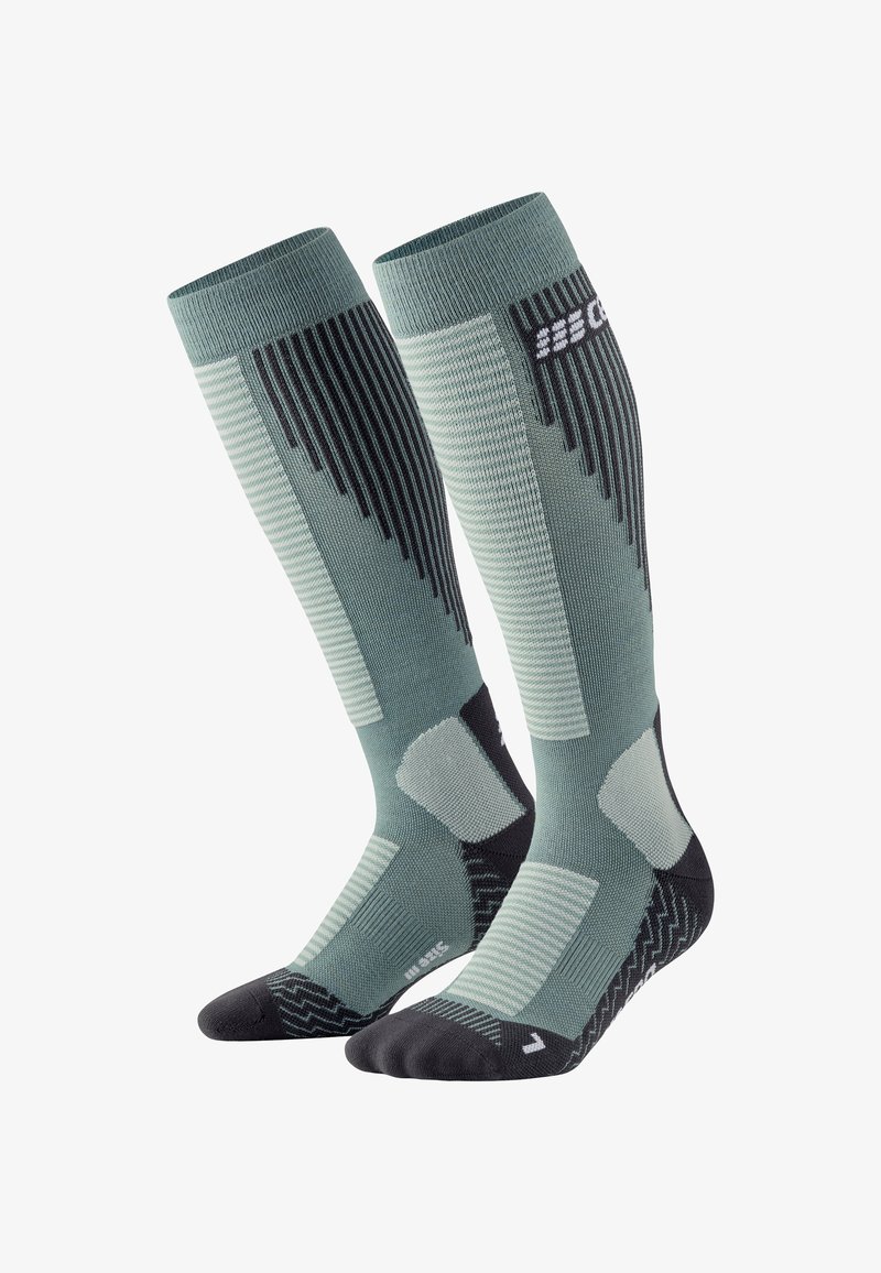 Calze compressive verdi e nere, con texture a coste e con motivo, tallone e punta rinforzati, con dettaglio del logo vicino alla parte superiore.