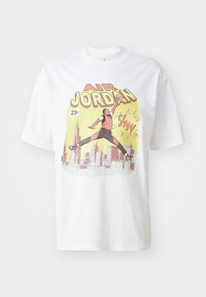 Balta medvilninė marškinėliai su spalvinga grafika, vaizduojančia krepšininką, tekstu "Air Jordan" ir miesto horizonto fone. Trumpomis rankovėmis.