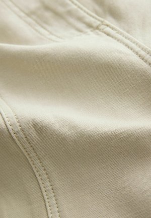 Hellbeige Stoff mit glatter Textur, der feine Nähte und ein sauberes, nahtloses Design aufweist.