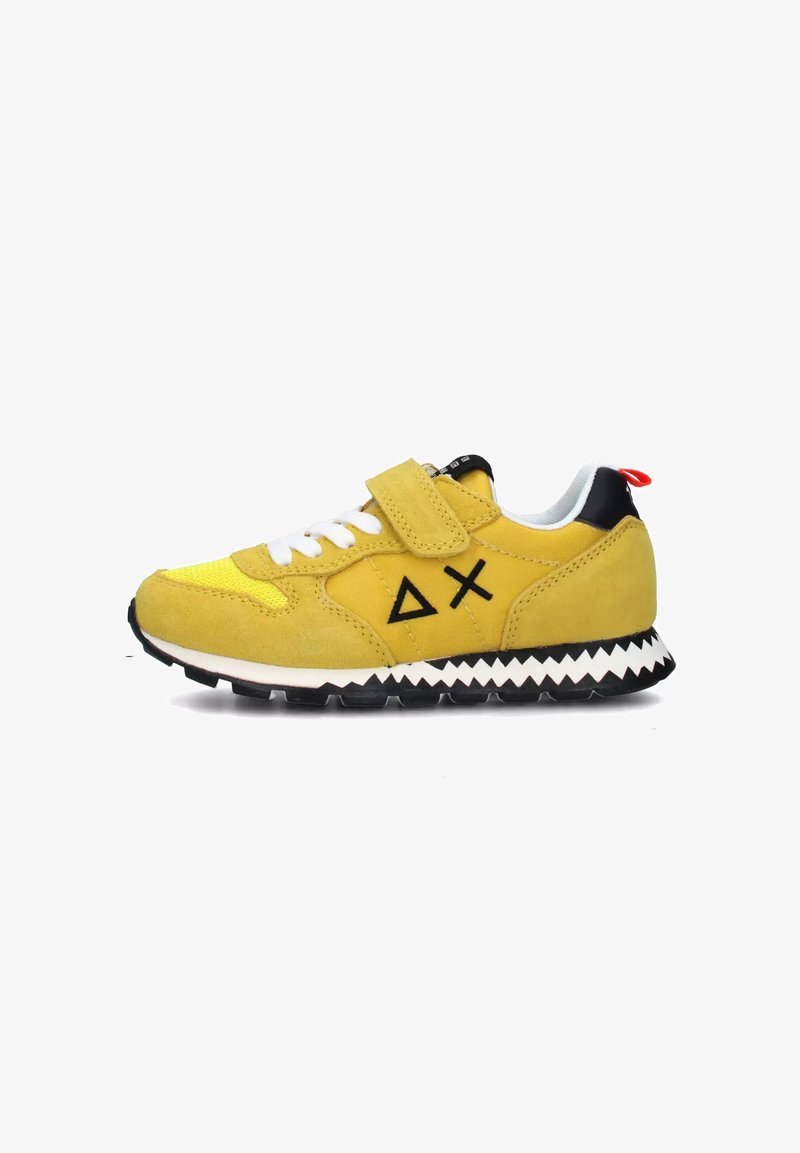 Sneaker giallo in camoscio con lacci bianchi, cinturino a strappo, accenti neri e suola zigzag. Presenta un dettaglio del logo sul lato.