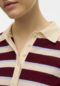 Pruhovaná polo tričko v barvách bordó, světle modré a krémové. Měkká látka, zapínání na knoflíky, s pěti knoflíky v přední části.