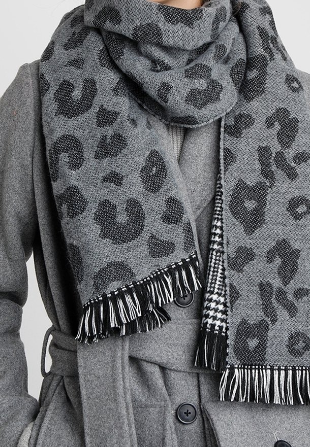 Manteau en laine gris avec des boutons noirs et une écharpe à motif léopard gris avec des franges noires et blanches.
