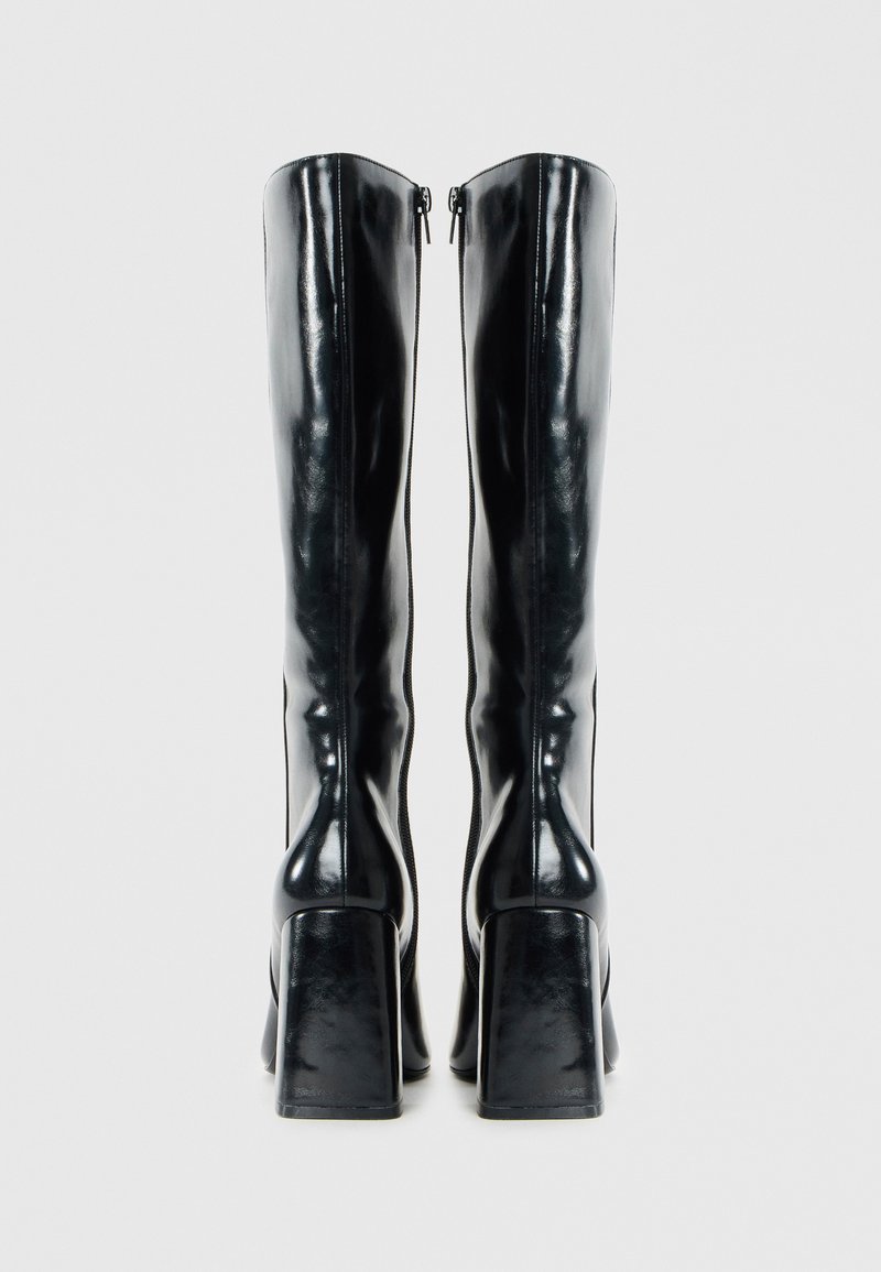Stivali neri in pelle lucida alte fino al ginocchio, con tacco quadrato alto e zip sul retro, caratterizzati da una texture liscia e un design aderente.