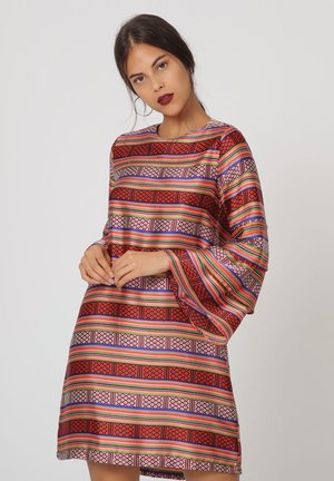 Un vestido de manga corta con un patrón vibrante de rayas rojas, azules y verdes, y diseños geométricos en una tela suave y brillante.