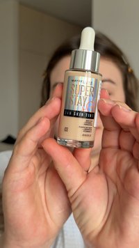 Maybelline Super Stay 24H Skin Tint, 30 ml, in einer Glasflasche mit Pipette. Hellbeige Farbton mit schwarzen und schillernden Etikettendetails.