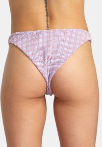 Bas de bikini à motifs violets et roses en tissu texturé, présentant une coupe taille basse et des côtés froncés pour un modelage supplémentaire.