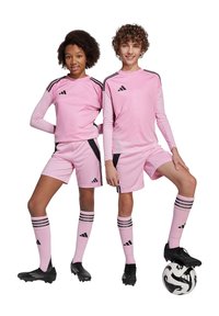 Uniformes de soccer athlétiques roses avec des accents noirs, comprenant des manches courtes, un short, des chaussettes longues et des chaussures à crampons noires. Un ballon de soccer est à leurs pieds.