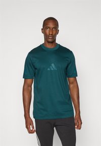 Tyrkysové sportovní tričko vyrobené z hladkého materiálu, s krátkými rukávy a decentním logem se třemi pruhy na hrudi. Čistý design a střih.