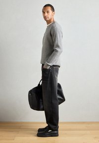 Gray ribbed sweater, black loose-fitting jeans with yellow stitching, black leather bag, and chunky black shoes. Simple, modern design.