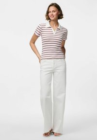 Roku īsā piedurkne polo krekls gaiši rozā krāsā ar tumšām svītrām, balts apkakle; apvienots ar brīviem baltajiem biksēm un neitrāliem sandalēm.