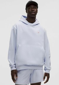 Lysebl�å hoodie lavet af bomuldsblanding, med en frontlomme og ribbede manchetter. Sammen med matchende shorts, sat mod en ensfarvet baggrund.