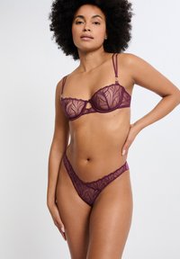 Ensemble soutien-gorge et string en dentelle violet foncé, avec broderies florales, bretelles réglables et découpe sur le soutien-gorge.