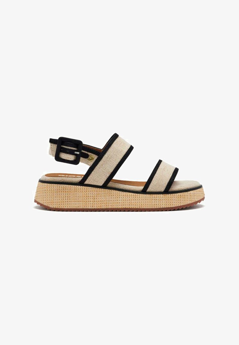 Sandalias de tela beige con acentos negros, hebilla ajustable, suela plana, superficie texturizada y diseño de punta abierta.